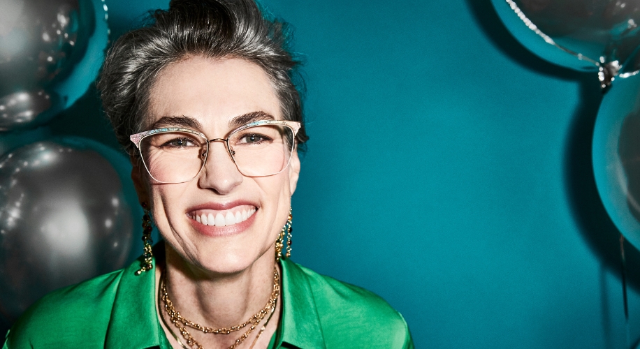 Woman wearing stylish eyeglasses with a clear frame and gold details, smiling brightly.