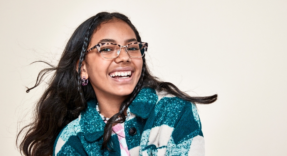 Person wearing leopard-print eyeglasses and a teal plaid jacket.