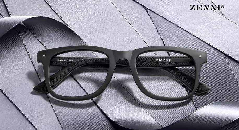 Black Zenni rectangular eyeglasses on a grey textured surface. Text on the frame: &quot;Made in China.&quot;