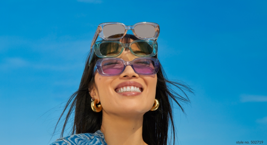 Woman wearing one pair of purple sunglasses, stacked with three additional pairs of sunglasses on her head. Text: &quot;style no. 502719&quot;.