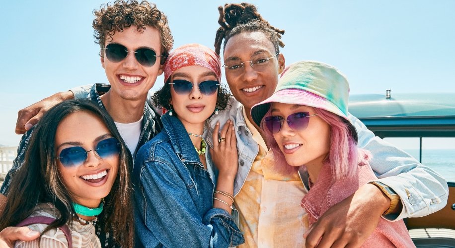 A group of diverse friends wearing stylish sunglasses, some with tinted lenses, smiling together.