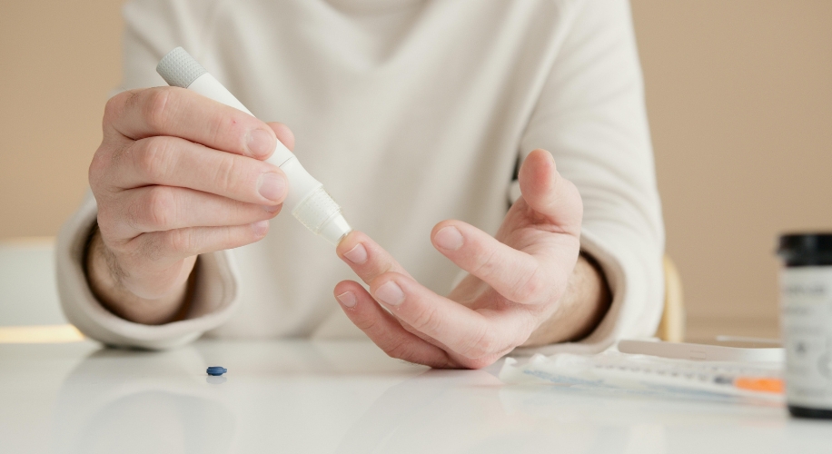 Hand using a lancet device to prick finger for blood glucose test.