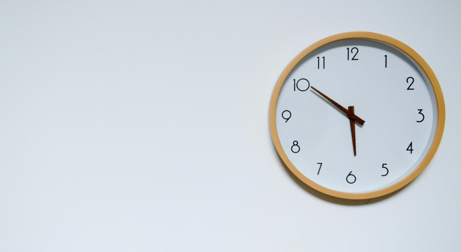 Round wall clock with wooden frame and white face showing time 10:09.