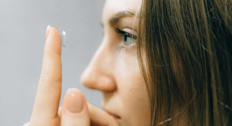 Contact lens balanced on a fingertip, close to the eye.