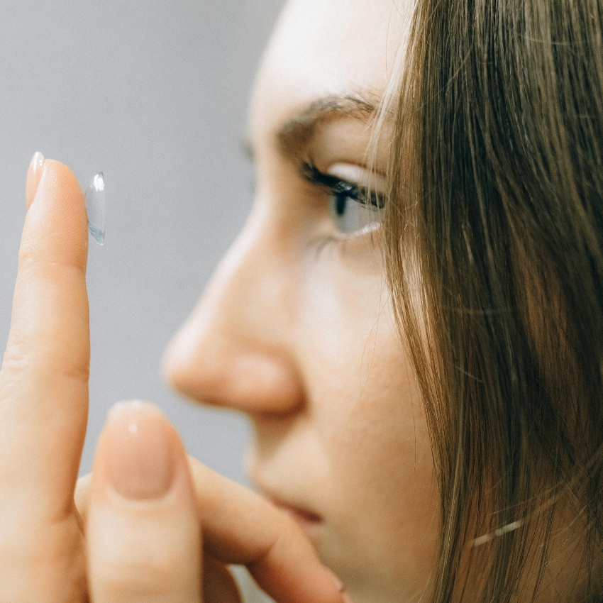 Person holding a contact lens on their fingertip, ready to place it in their eye.