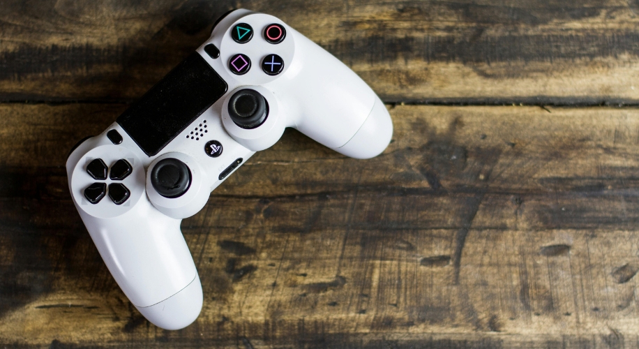 White gaming controller with black buttons and colorful shapes on a wood surface.