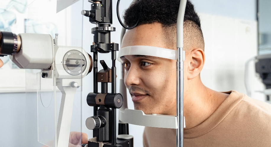 Man undergoing an eye examination using a slit lamp microscope.