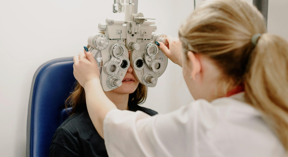 Optometrist uses a phoropter to measure patient&#039;s eye prescription during an eye exam.