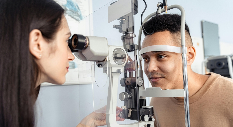 Optometrist performing an eye exam on a patient using a slit lamp.