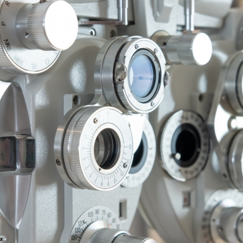 Close-up of a phoropter, an ophthalmic testing device with multiple dials and lenses for eye exams.