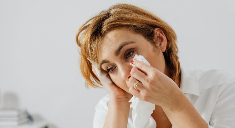 Woman using a tissue to wipe her tear.