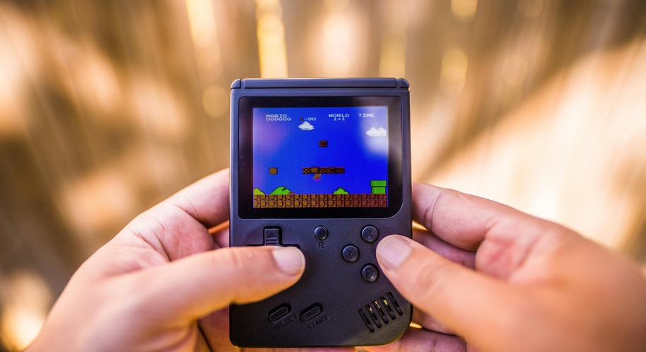 Person holding a handheld video game console playing Super Mario Bros.