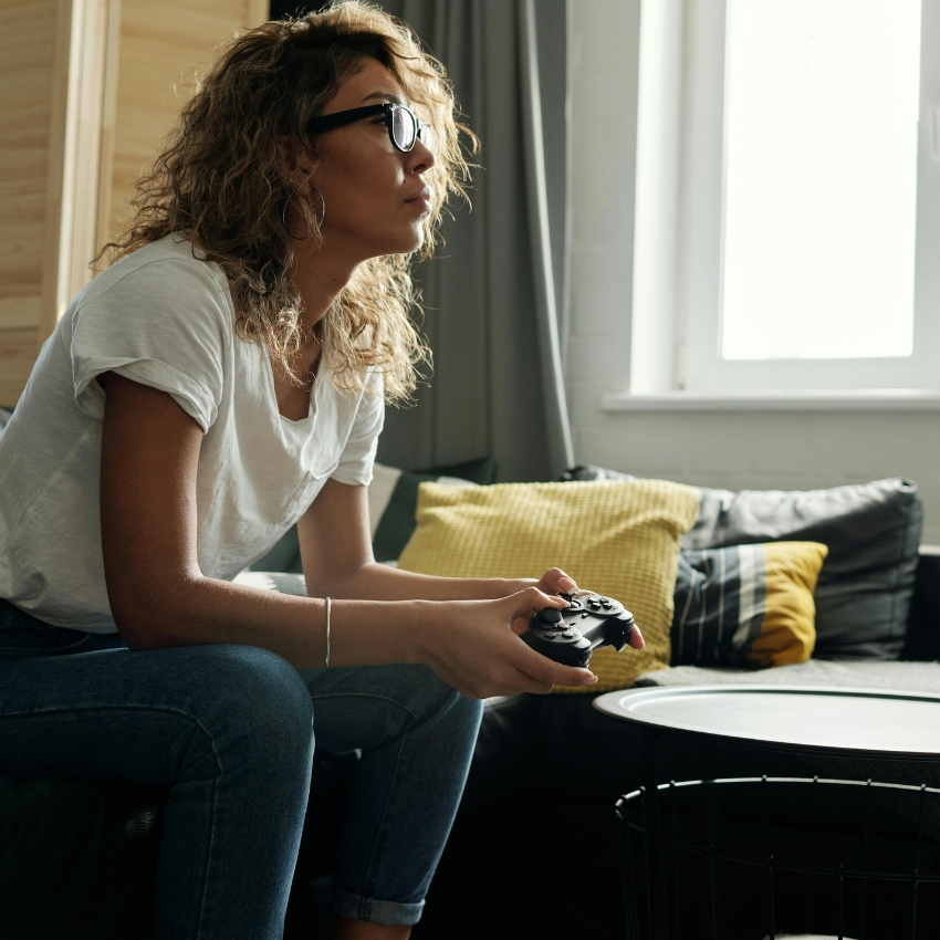 Person holding a game controller while seated on a couch.