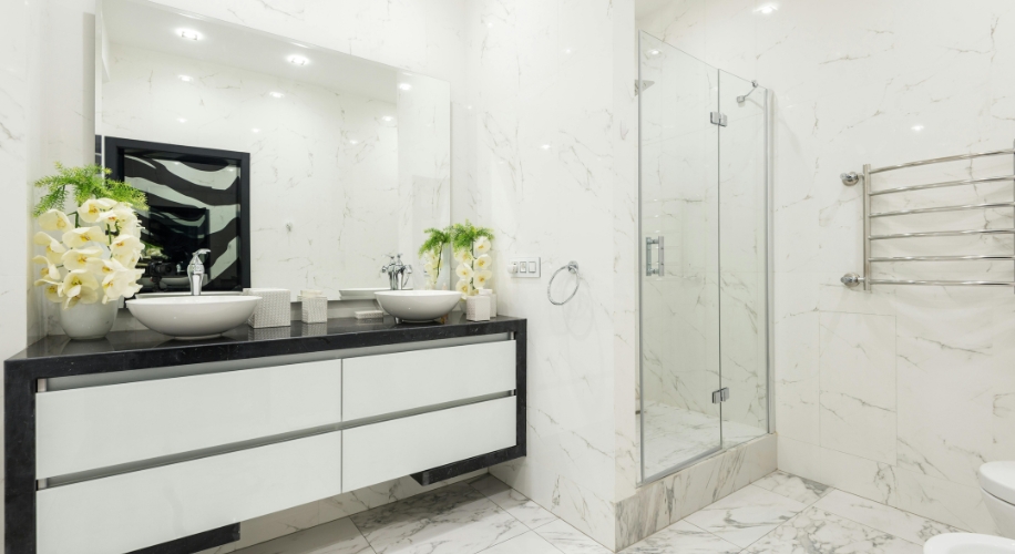 Modern bathroom with a double sink vanity, marble countertops, rectangular mirror, and glass shower enclosure.