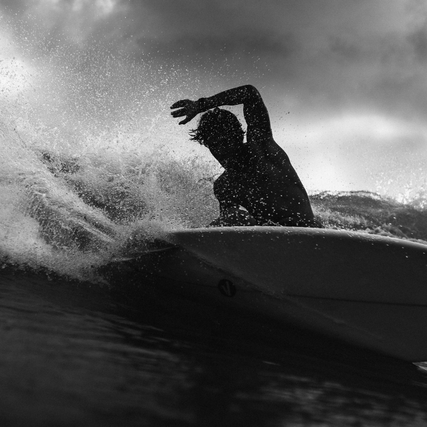 Silhouette of a surfer riding a wave on a surfboard.