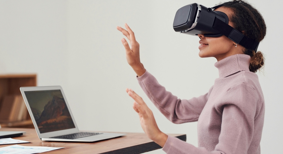 Person using a virtual reality headset, interacting with virtual objects, with a laptop nearby.