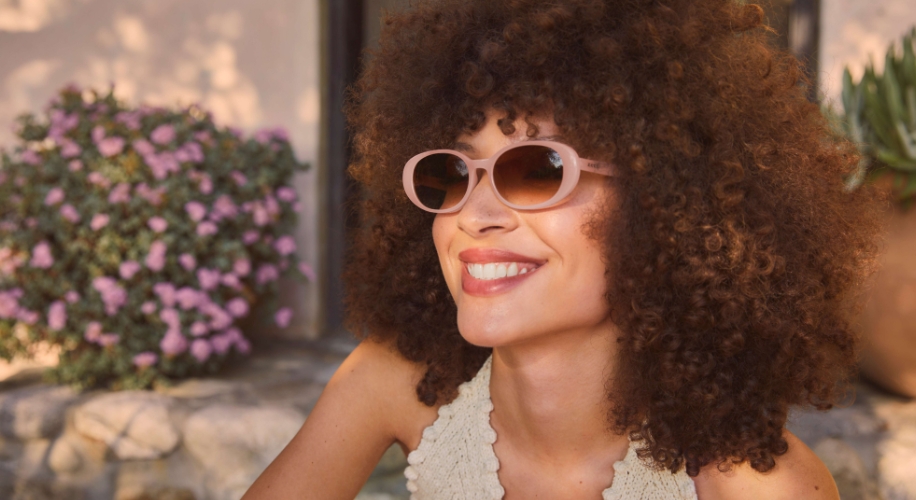 Woman wearing pink sunglasses, smiling.