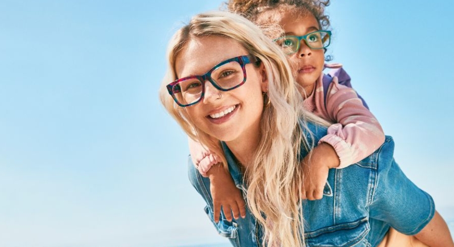 Two people wearing colorful eyeglasses; the adult in blue and the child in green.