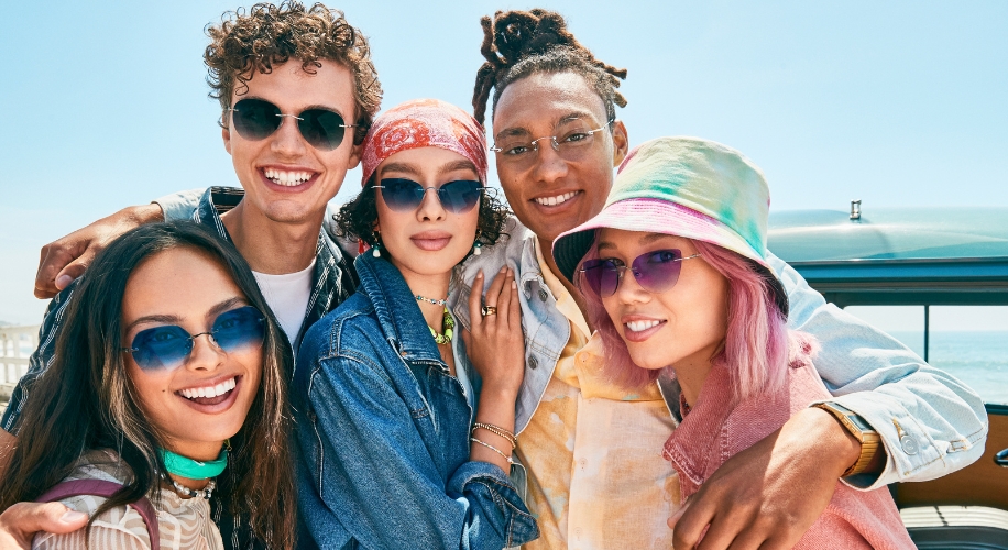 Five people wearing stylish sunglasses, displaying various frames and lens colors in a sunny setting.