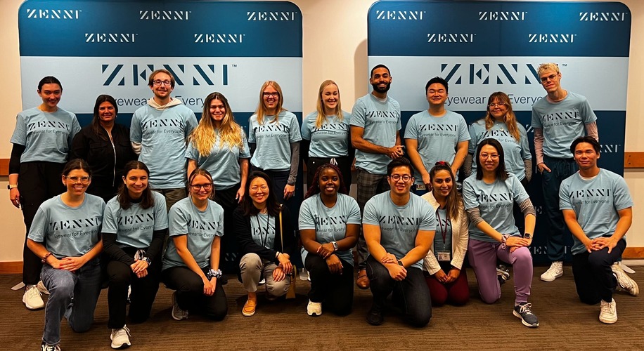 Group wearing Zenni shirts with &quot;Eyewear for Everyone&quot; in front of Zenni branded backdrop.