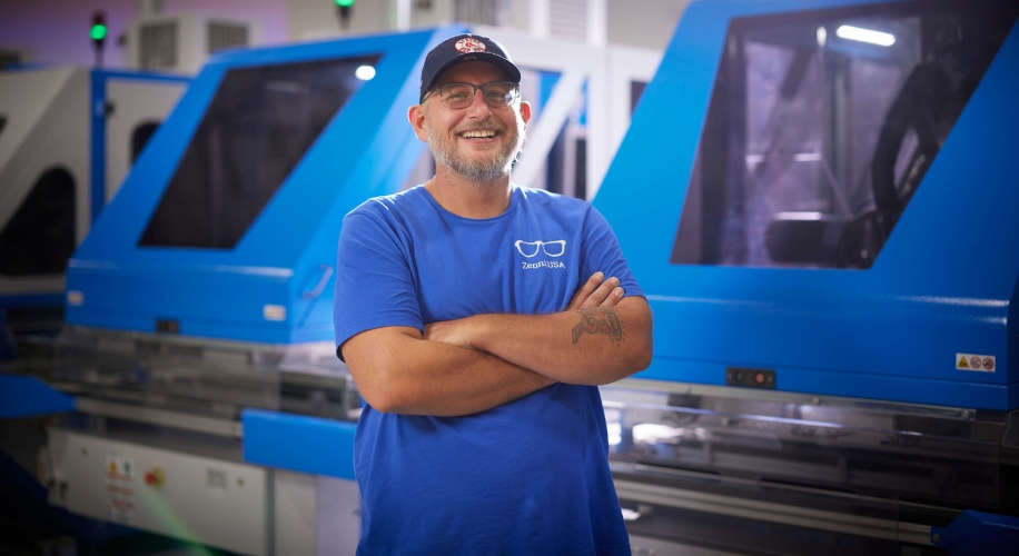 Man in blue &quot;Zenith USA&quot; shirt and cap standing in front of machine equipment.