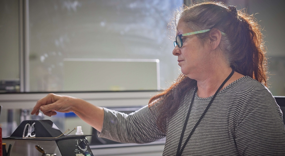 Woman adjusting glasses on a cleaning device on a desk.