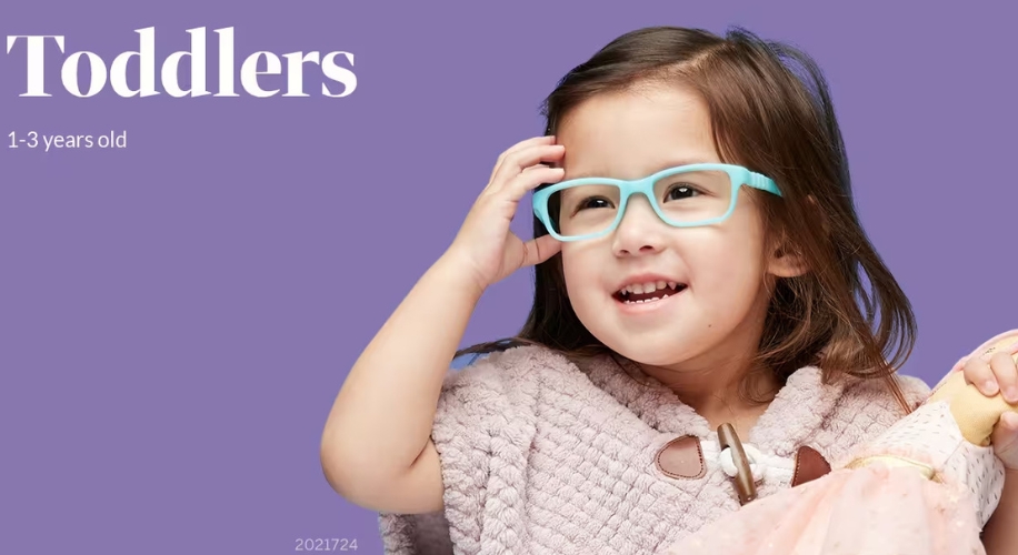 Toddlers 1-3 years old. Little girl wearing blue glasses and holding a doll.