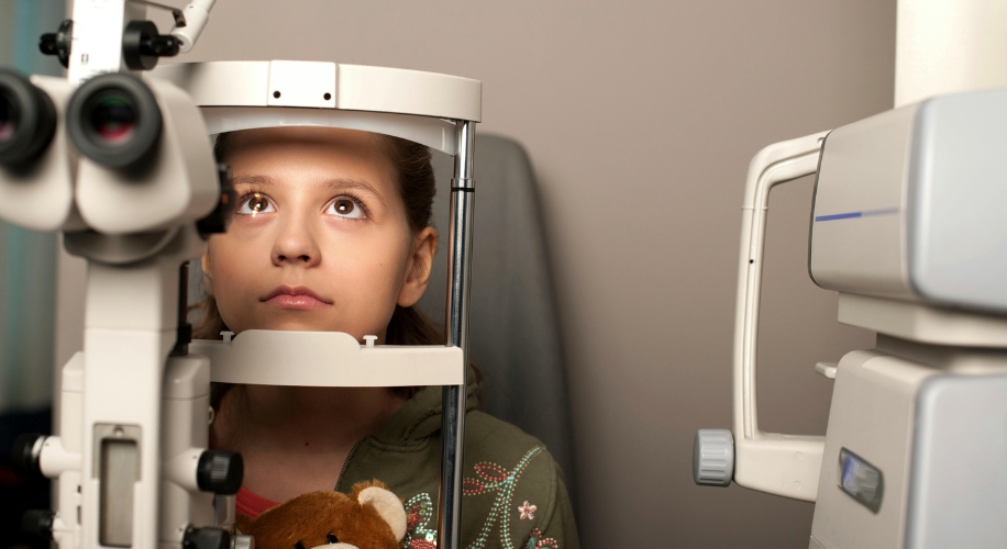 Child using an eye examination device at an optometrist&#039;s office.