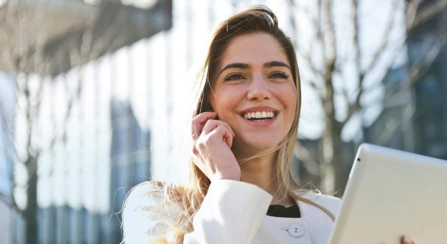 Person using a tablet and smiling outdoors.