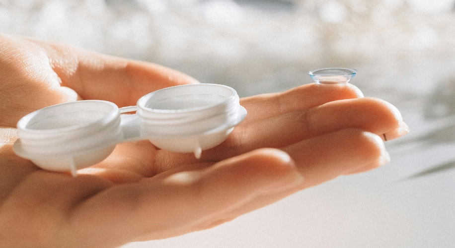 Contact lens case and lens resting on a hand.