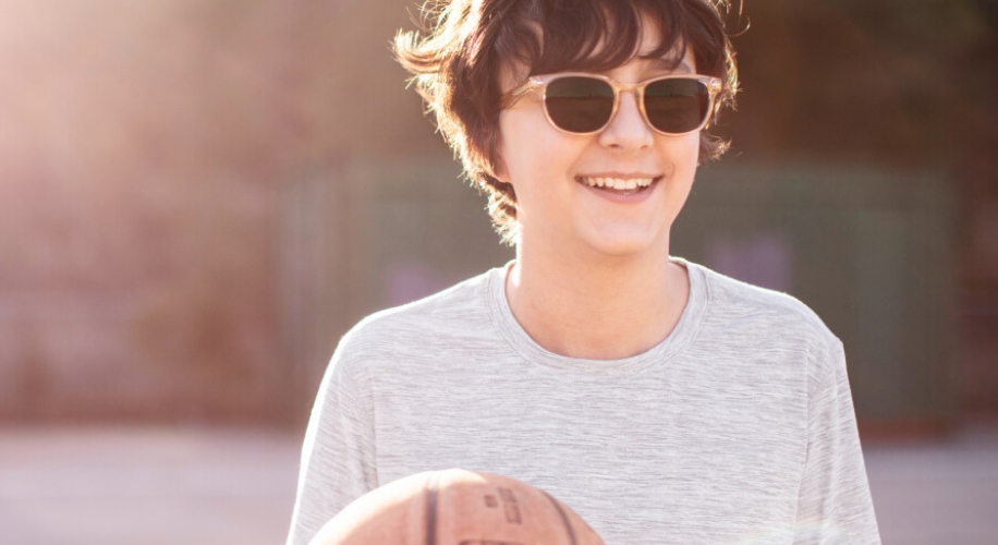 Smiling person wearing sunglasses holding a basketball.