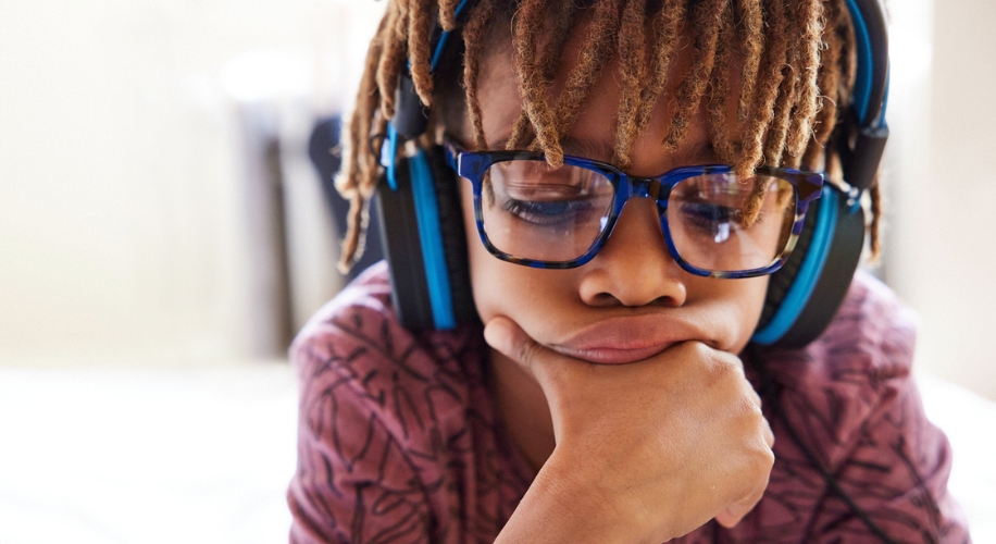 Child wearing blue headphones and glasses.