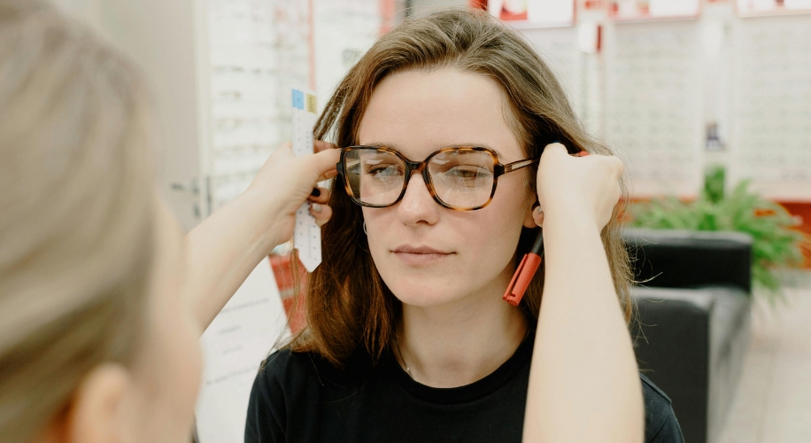 Woman trying on large tortoiseshell glasses.