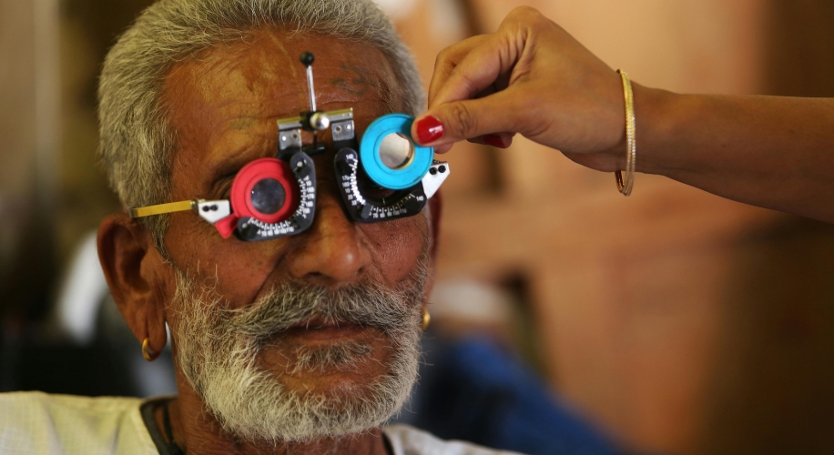 Optometry trial frame on a person’s face, lenses being adjusted by an optometrist’s hand.