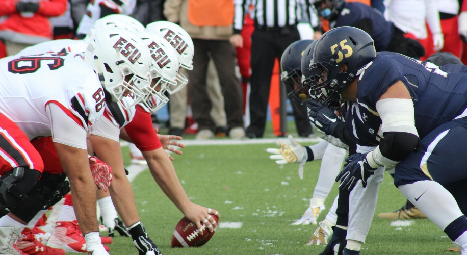 Football players in formation, about to snap the ball.