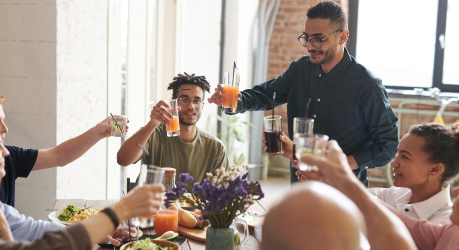 People toasting with glasses around a table with food and flowers.