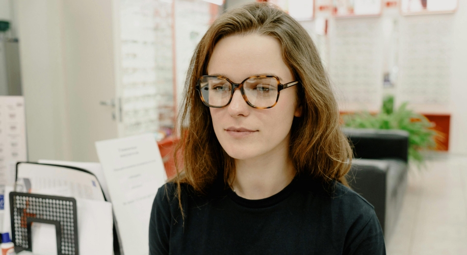 Woman wearing tortoiseshell glasses inside an optical store.