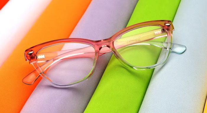 Pink transparent eyeglasses with layered colorful background.