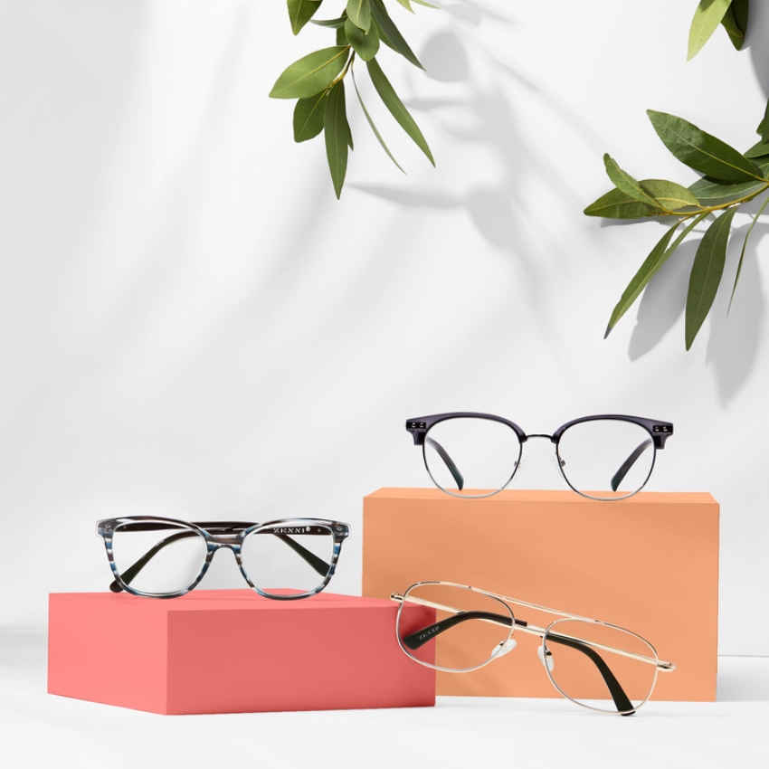 Three pairs of Kensie eyeglasses displayed on colorful blocks.