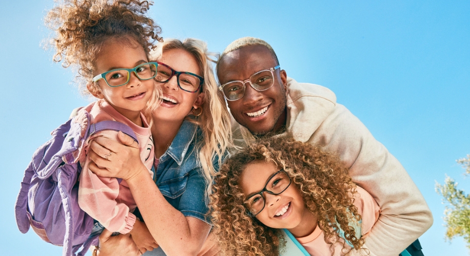 Four people wearing stylish eyeglasses, two pairs with green frames and two with clear frames.