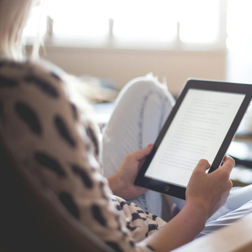 Person holding a tablet displaying text.