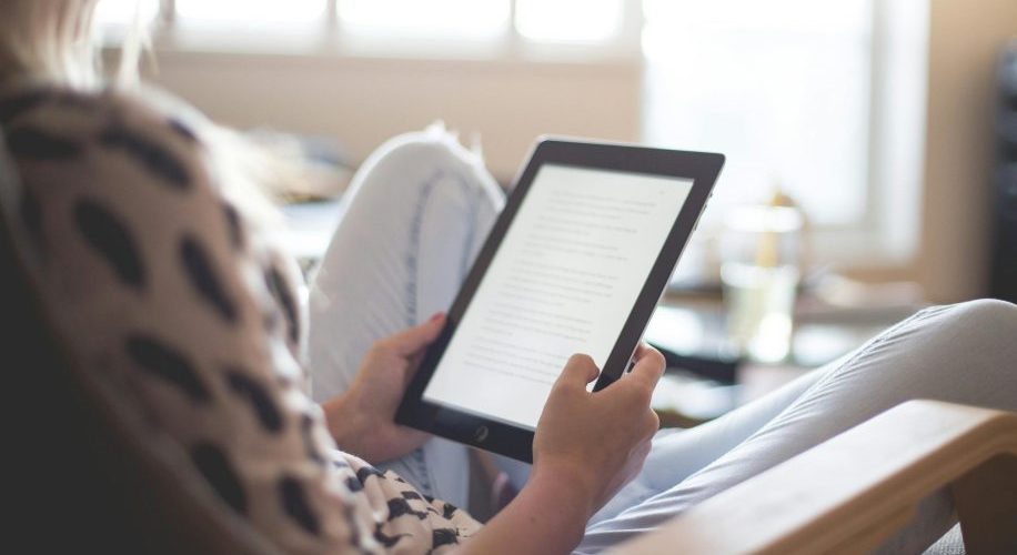 Tablet displaying text, held by a person in casual clothing.