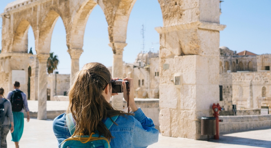 Person taking a photo of ancient stone arches.