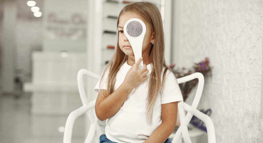 Child holding a handheld electronic device with a circular patterned front to her face.