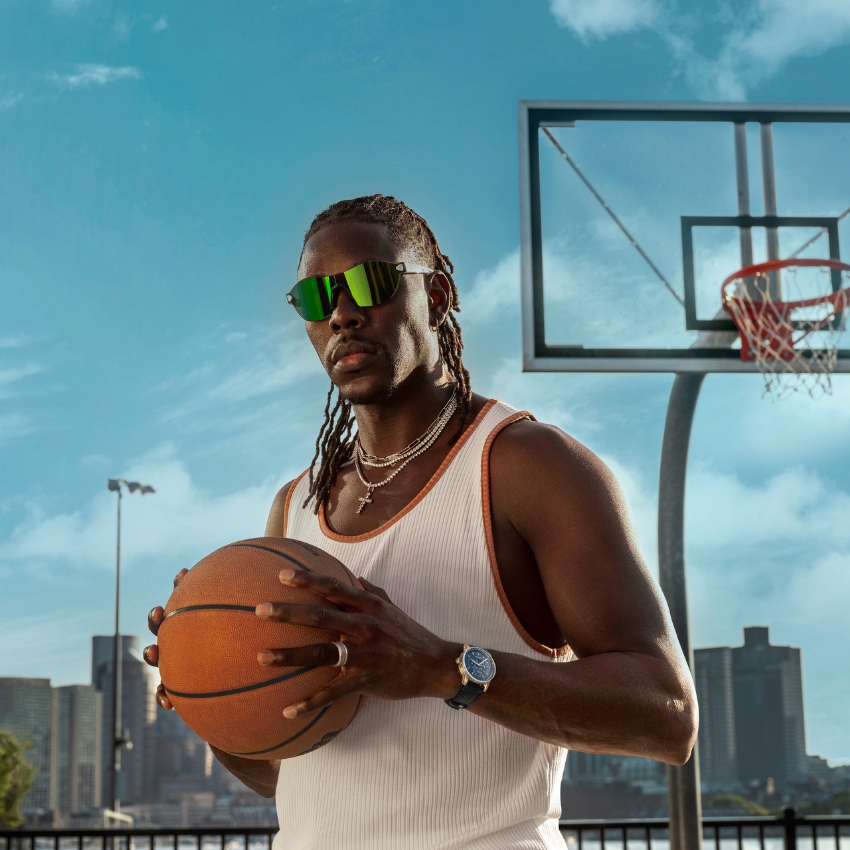 Man wearing reflective sunglasses, holding a basketball, and wearing a silver watch.