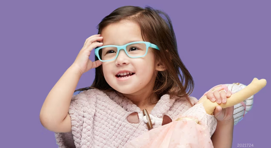 Child wearing blue glasses, holding a doll.