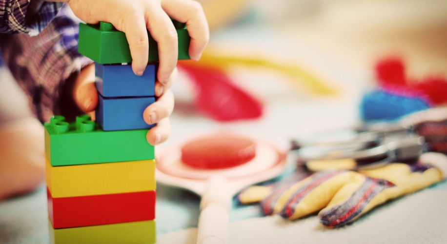 Child stacking colorful building blocks.